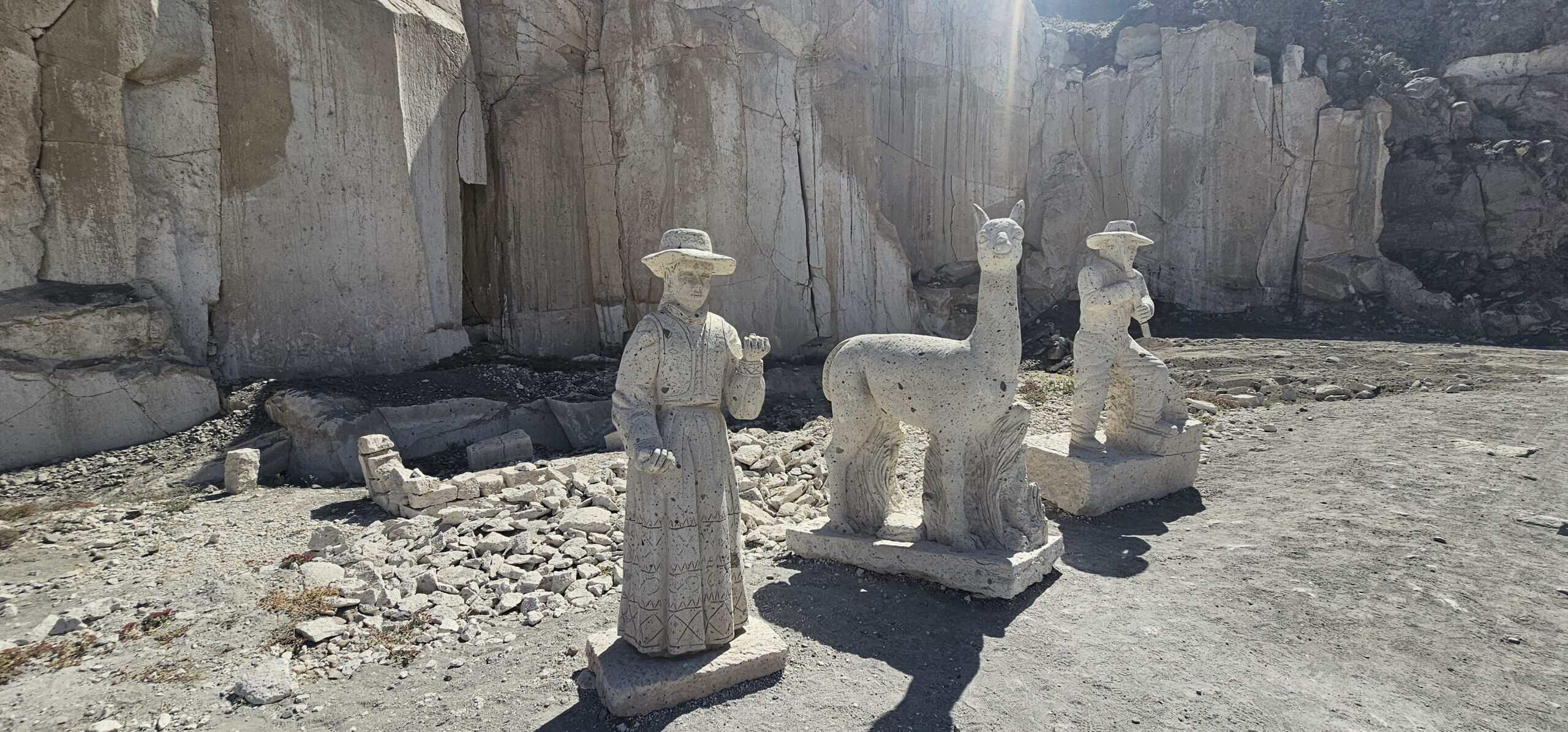 White volcanic stone sculptures of a woman, alpaca, and stone worker at the Ruta del Sillar quarry near Arequipa, Peru