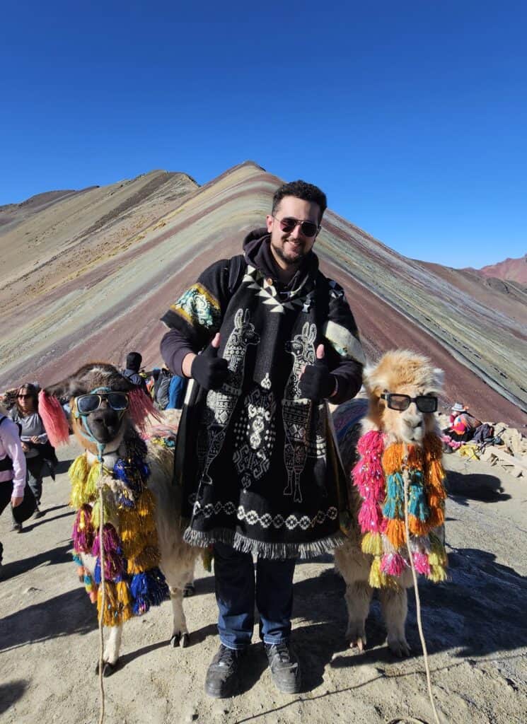 Traveler posing with colorful llamas at Rainbow Mountain near Cusco, Peru